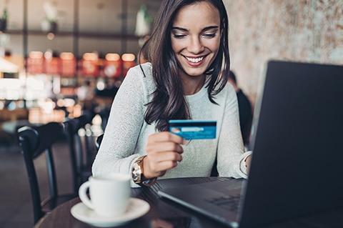 Lady sitting at coffee shop with computer and banking card