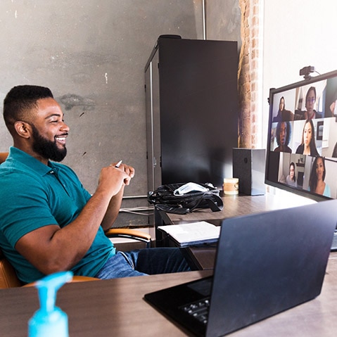 Man sitting at desk blue shirt laptop 