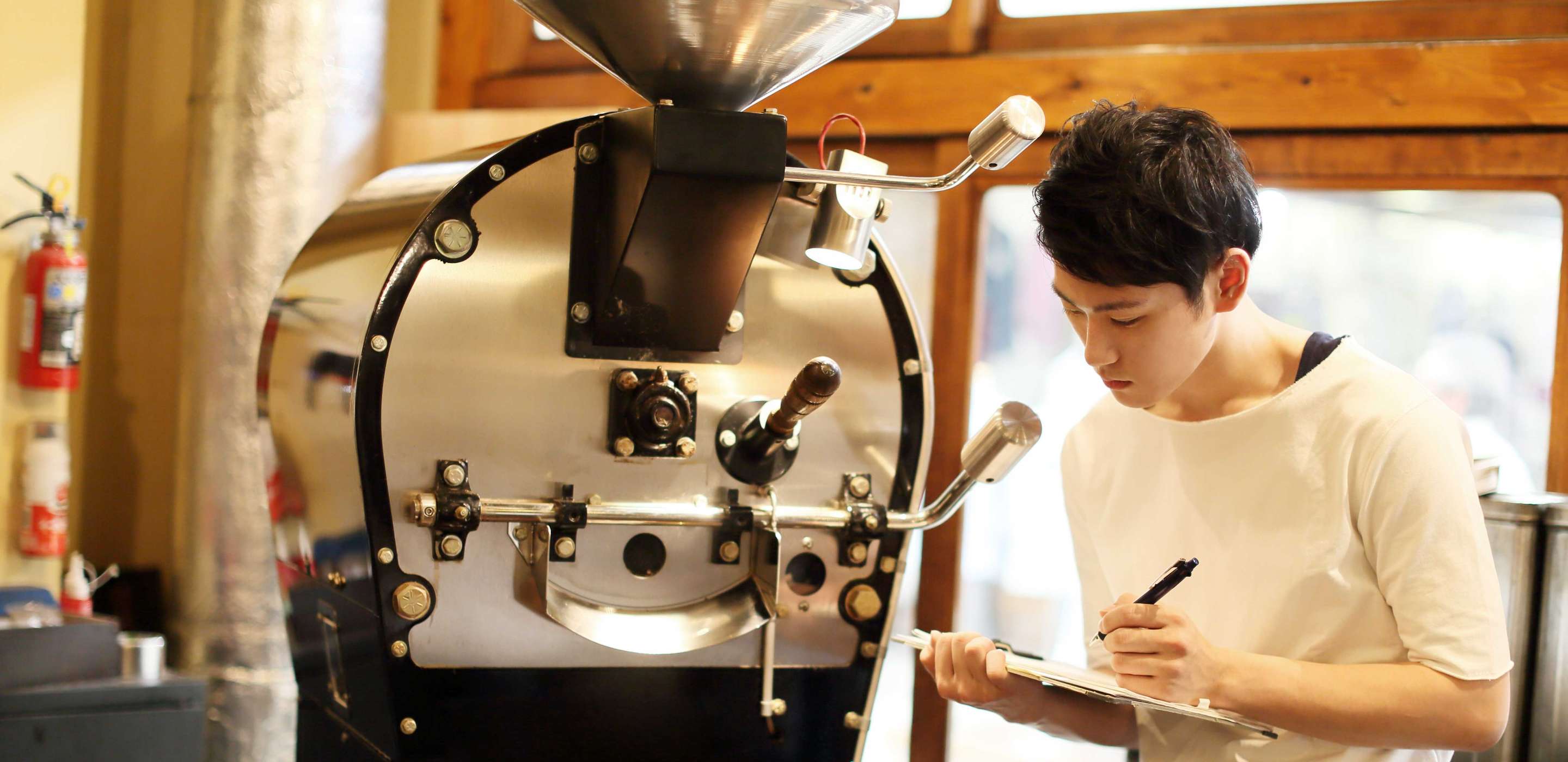 A man looking at a big coffee bean machine 