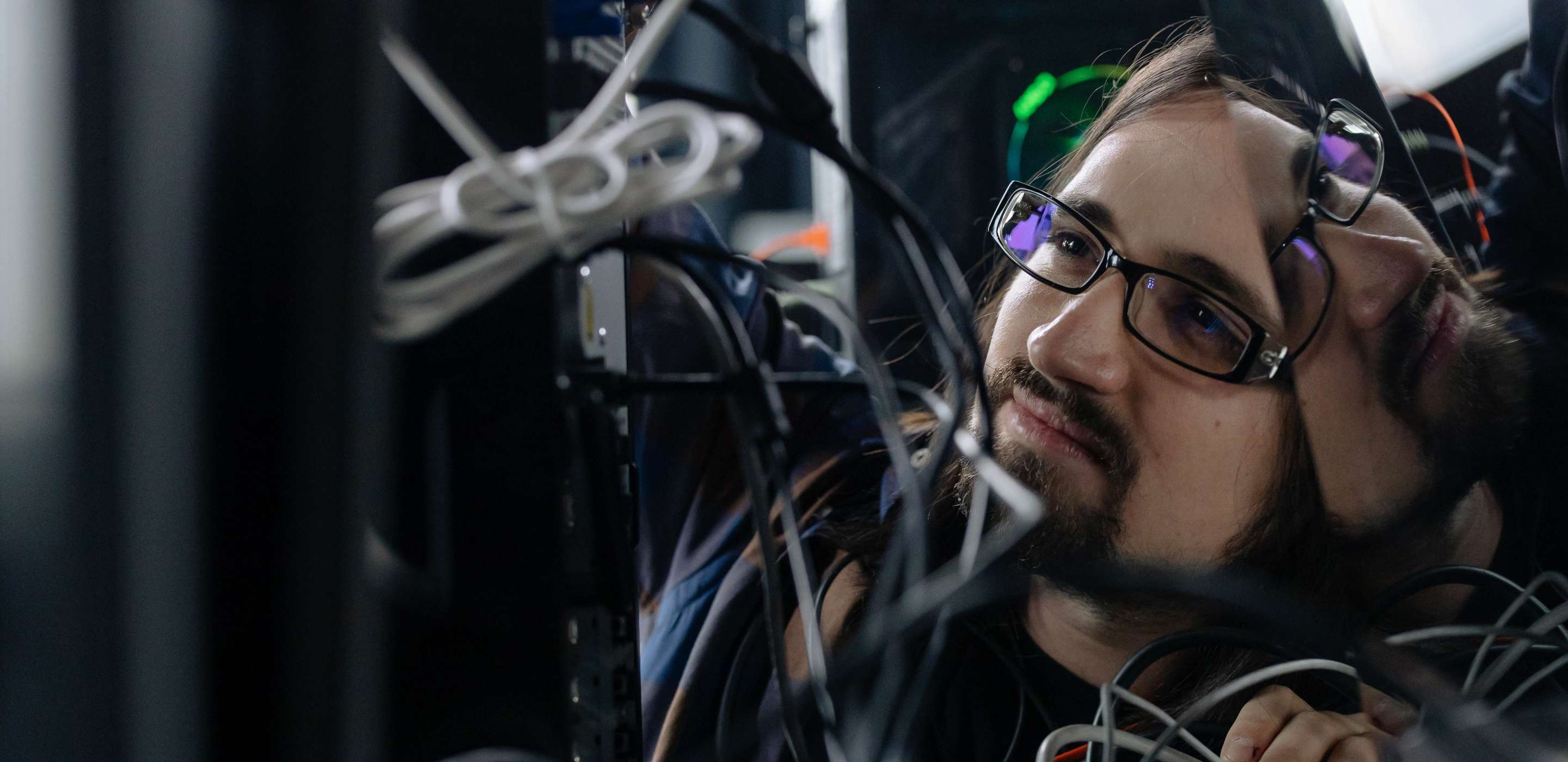 A man wearing glasses surrounded by wires