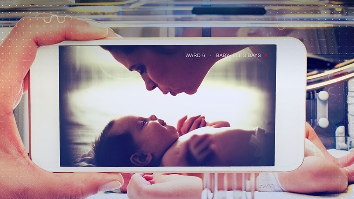 A photo on a screen of a mother going to kiss her baby