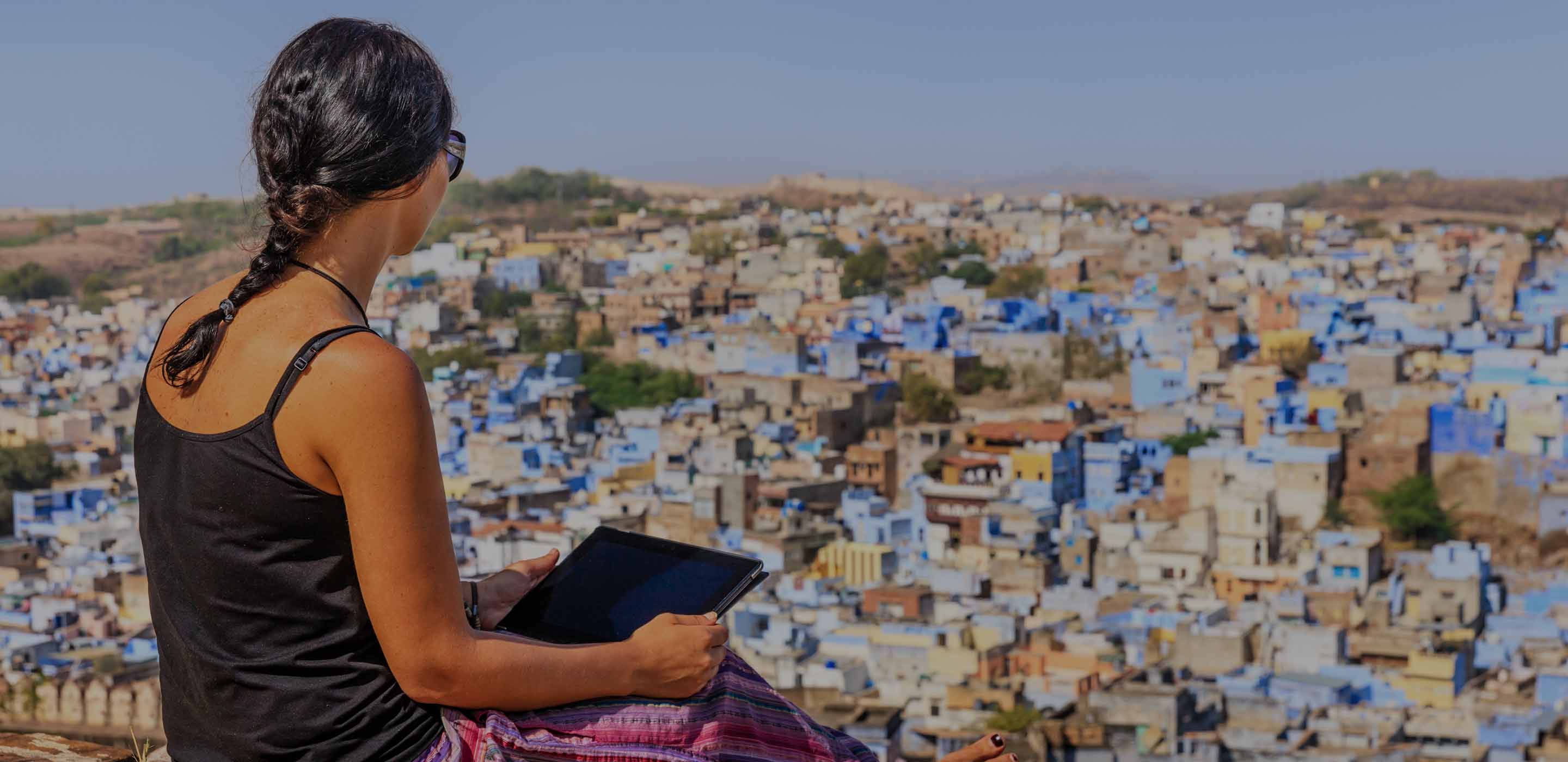 Woman sitting with her tablet overlooking a city below