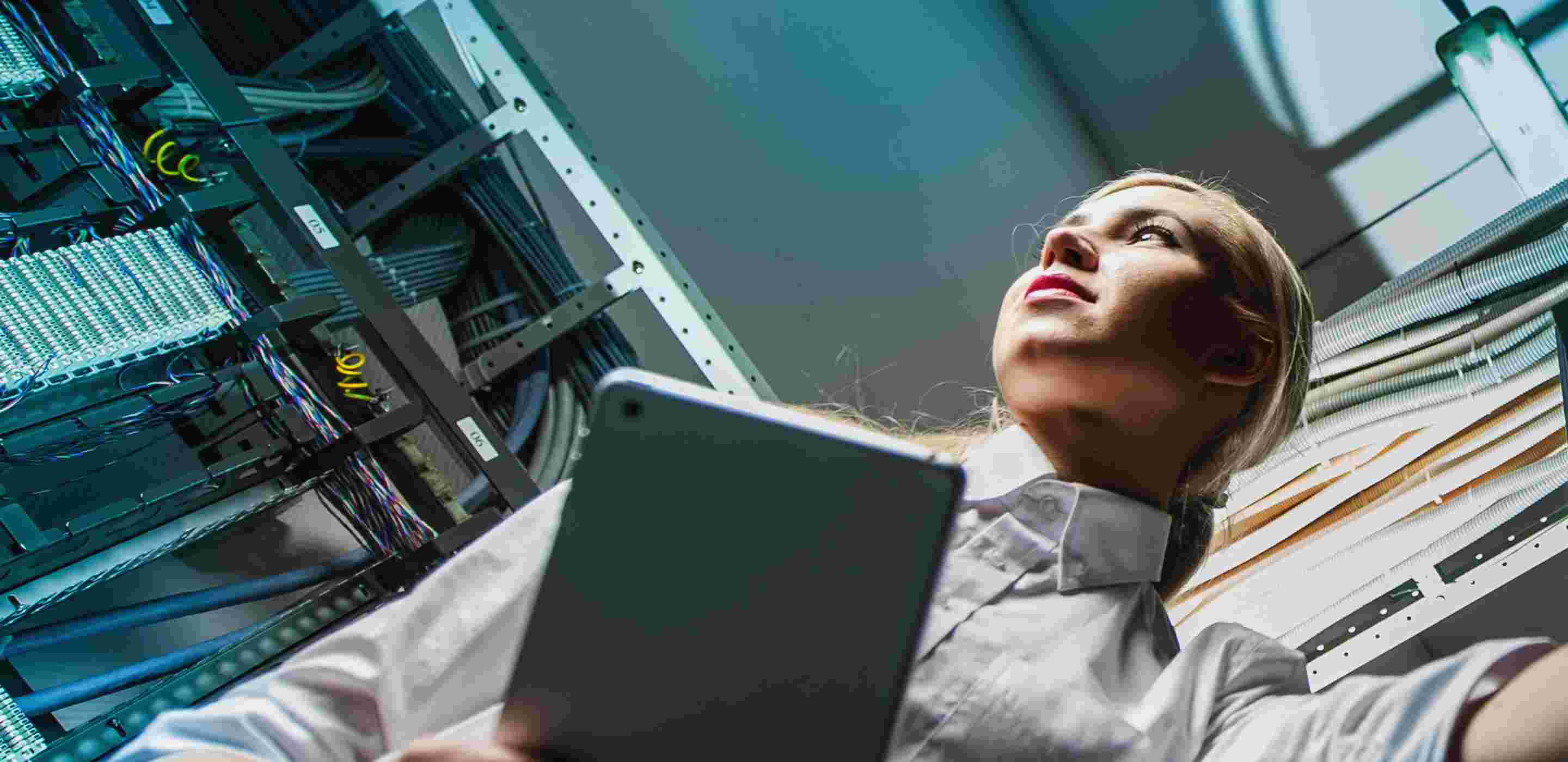 A woman holding a tablet in a server room