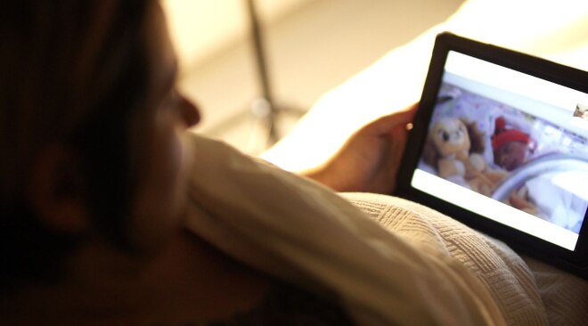 A woman looking at her newborn on an iPad