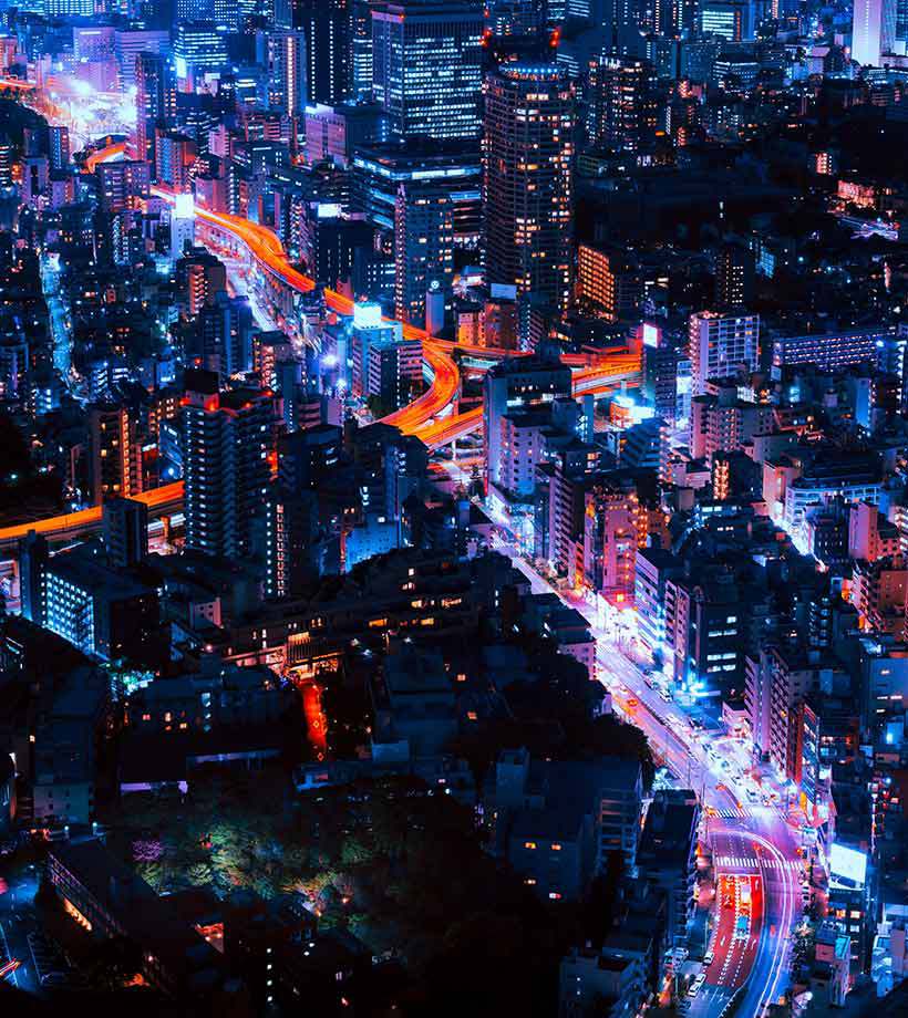 A top view of city builds and streets at nights with lights on