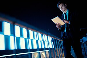 Young and handsome busnissman on the building balcony at night, holding his digital tablet