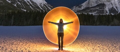 Woman with open arms standing in front of a glowing circle