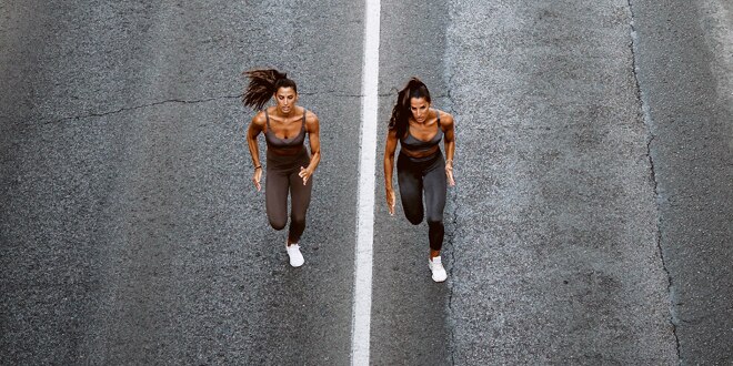 Two women running down a tar road