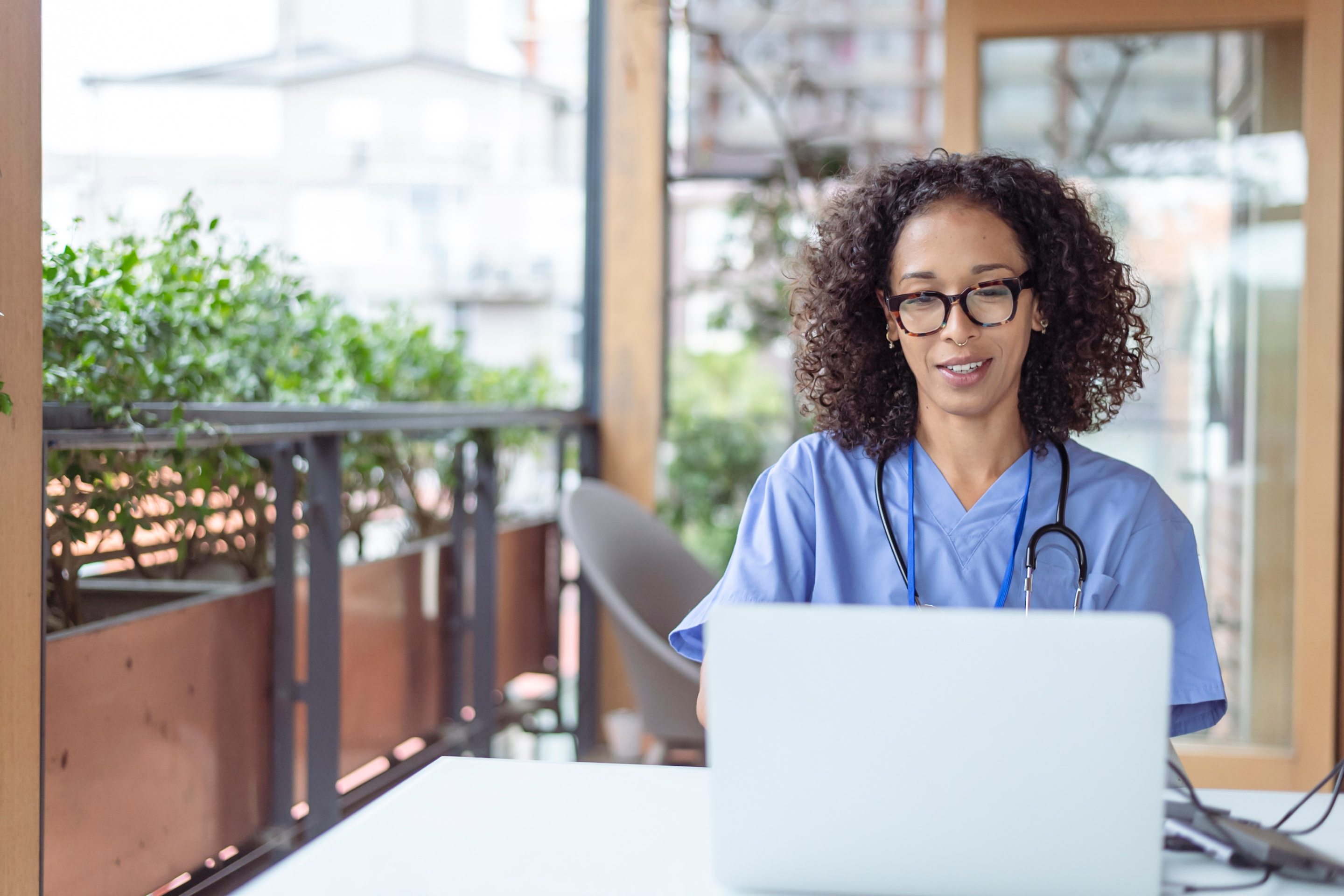 A woman wearing health care uniform looking a laptop screen