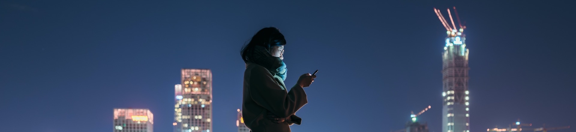 A person standing silhouetted against a city at night
