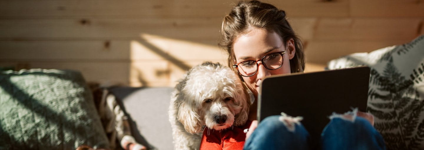 Woman working on tablet while her dog watches