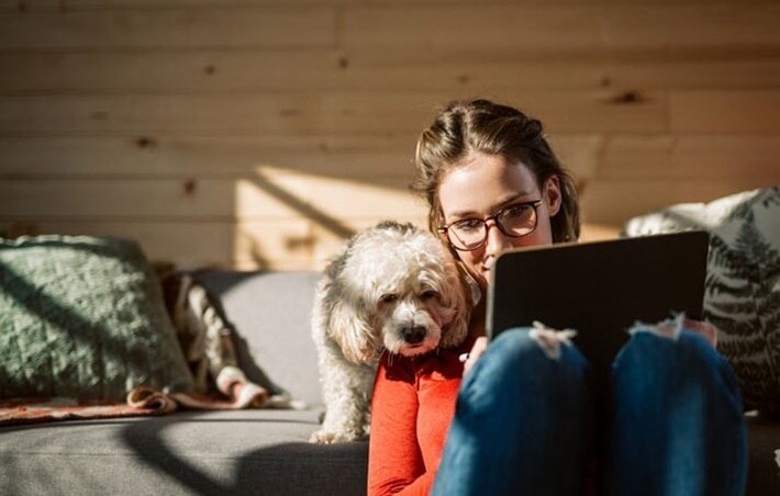 Woman working on tablet while her dog watches