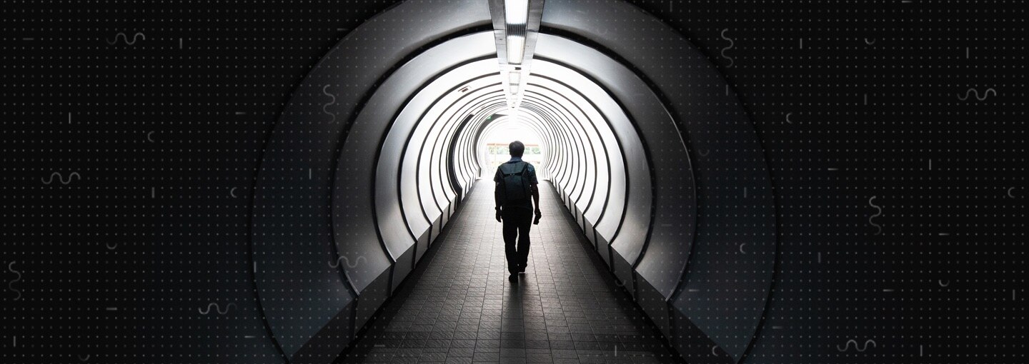 A person walking down a tunnel towards the exit