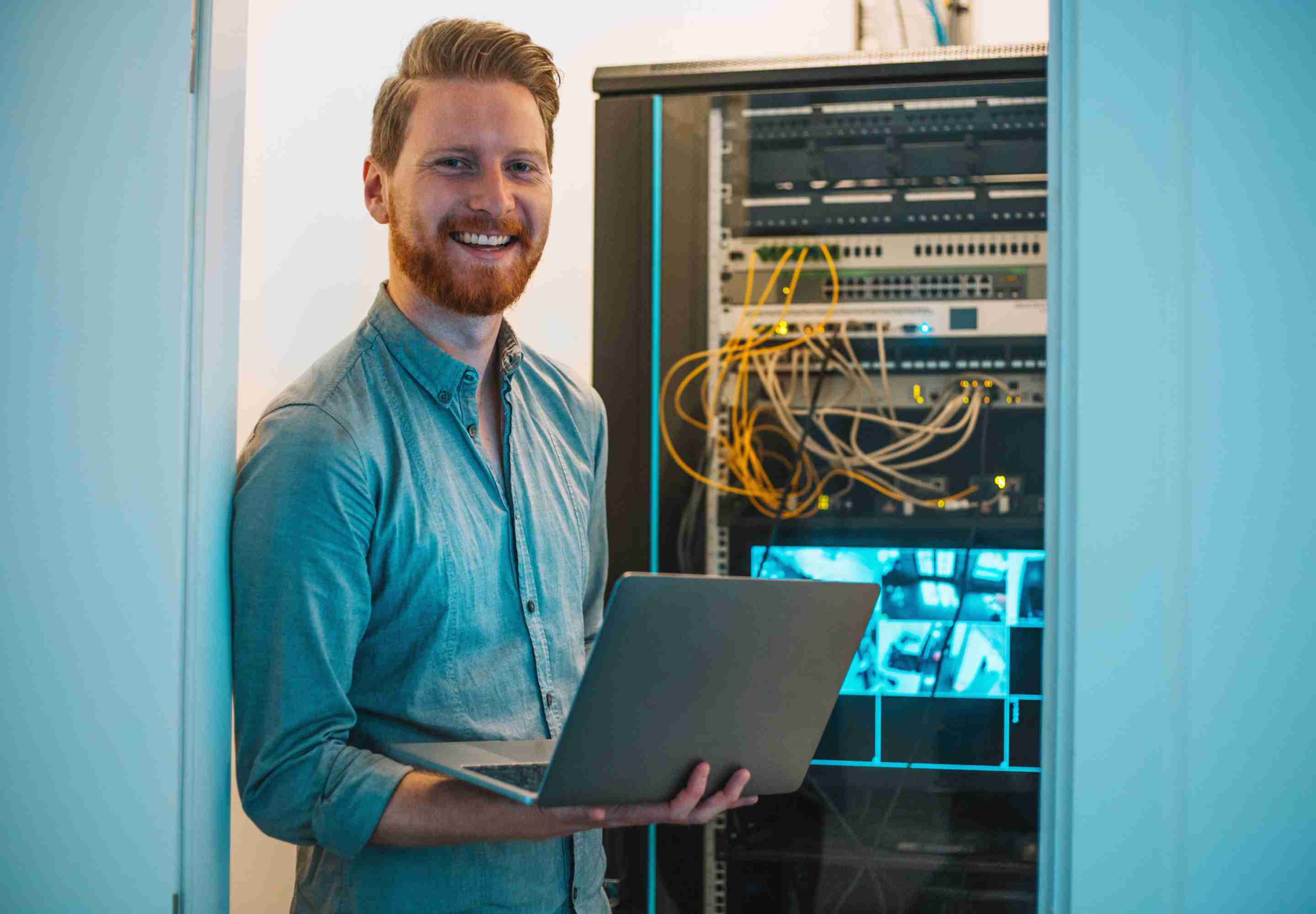 Man standing in a server room with a laptop