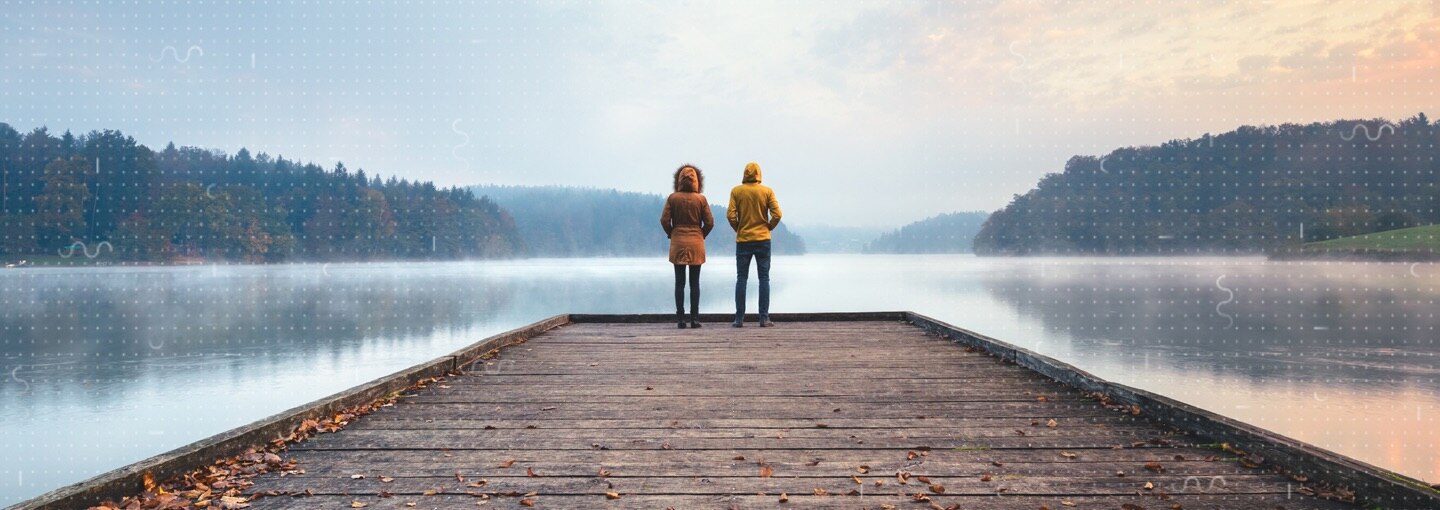 Two people standing at the end of a pier 